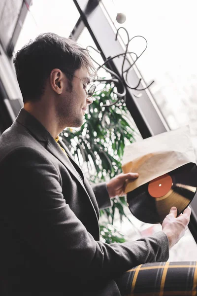 Jeune homme en lunettes de soleil tenant un record de vinyle dans les mains — Photo de stock