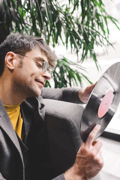 Cheerful young man in sunglasses holding vinyl record in hands — Stock Photo