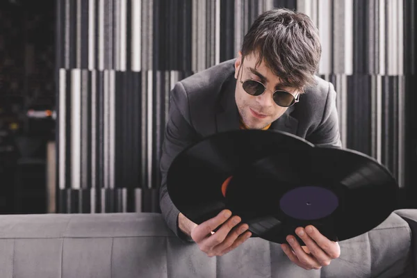 Stylish young man in sunglasses holding retro vinyl records — Stock Photo