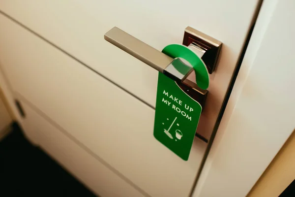 Дверная ручка с зеленым символом с макияжем в номере, уборка в отеле — стоковое фото