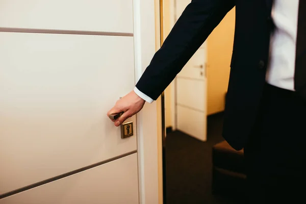 Visão parcial do homem segurando a maçaneta da porta e entrando no quarto do hotel — Fotografia de Stock