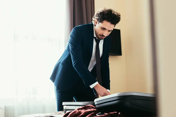 Hombre de negocios guapo con bolsa de viaje en la cama en la habitación de hotel — Stock Photo