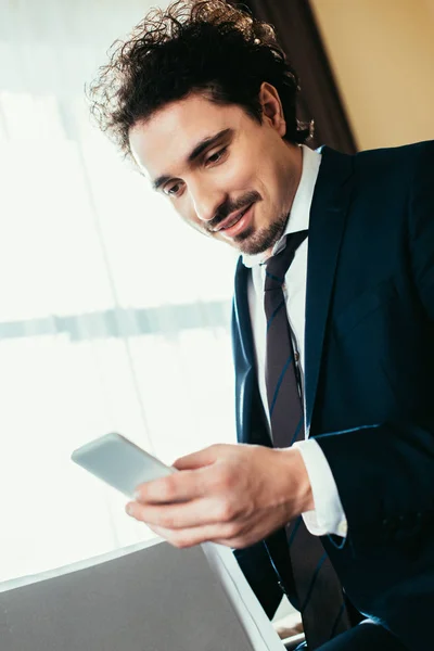 Bell'uomo d'affari che parla su smartphone e tiene documenti in camera d'albergo — Stock Photo