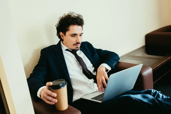 Homem de negócios com café para ir trabalhar no laptop no quarto de hotel — Fotografia de Stock
