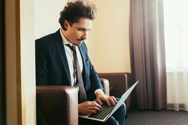 Adult businessman in suit working on laptop in hotel room — Stock Photo