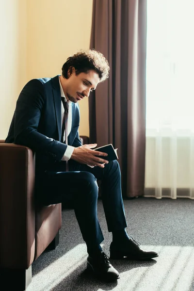 Hombre de negocios con pasaporte y sentado en la habitación de hotel - foto de stock