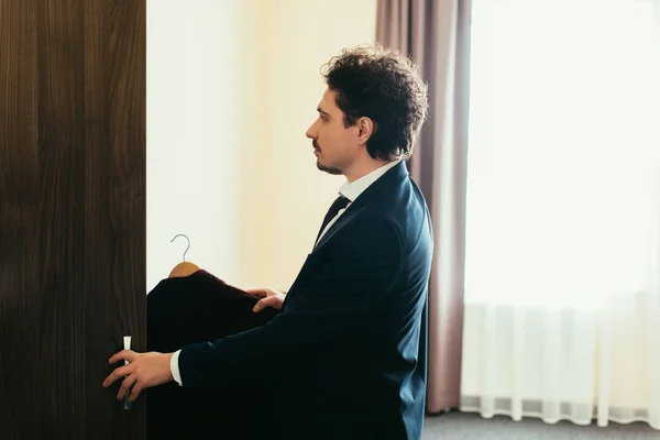 Uomo d'affari in giacca e cravatta prendere i vestiti dal guardaroba in camera d'albergo — Foto stock