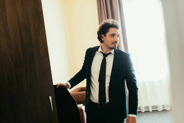 Красивый бизнесмен берет одежду из шкафа в гостиничном номере — стоковое фото