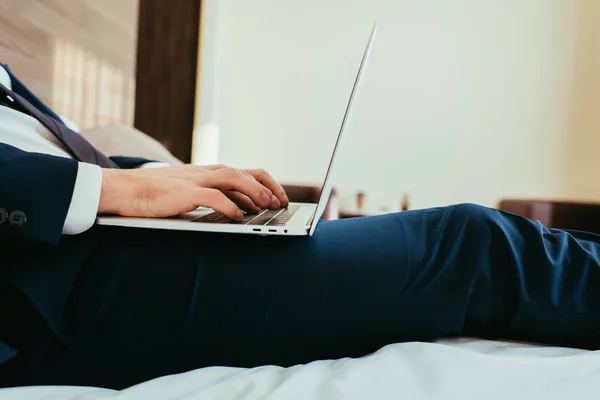 Vista cortada de homem de negócios digitando no laptop no quarto de hotel — Fotografia de Stock