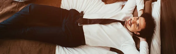 Vue du dessus de l'homme d'affaires souriant se détendre sur le lit dans la chambre d'hôtel — Photo de stock