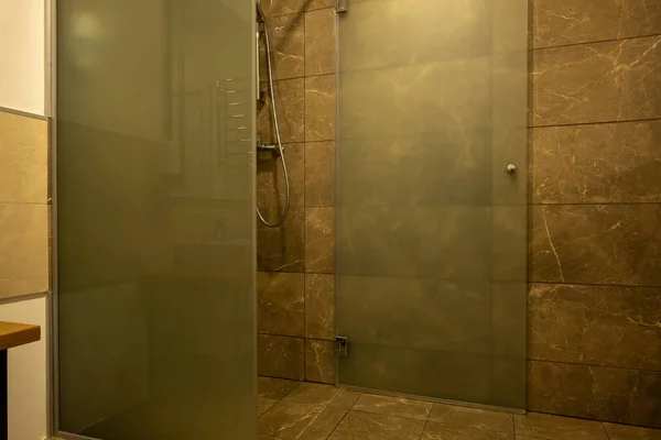Badezimmerausstattung mit braunen Fliesen und Glasduschkabine — Stockfoto