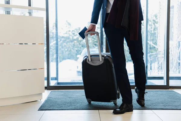 Ausgeschnittener Blick auf Geschäftsmann mit Reisepass und Reisetasche, der ins Hotel kommt — Stockfoto