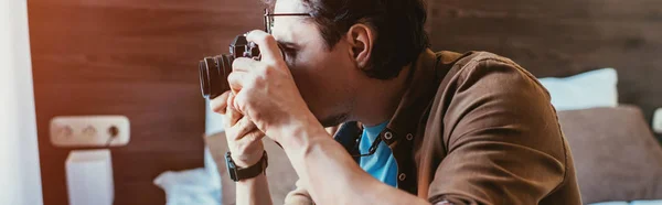 Взрослый мужчина в очках делает фото на камеру в гостиничном номере — стоковое фото