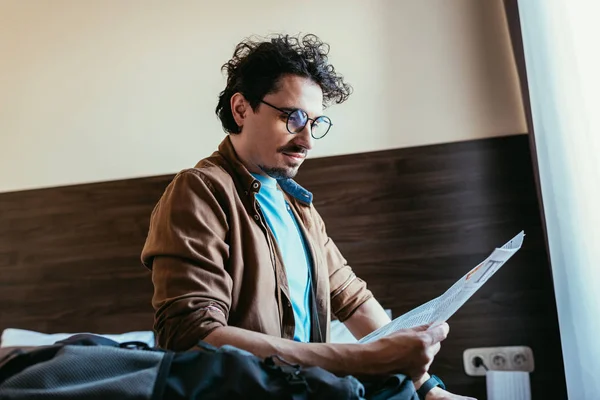 Schöner männlicher Reisender liest Zeitung im Hotelzimmer — Stockfoto