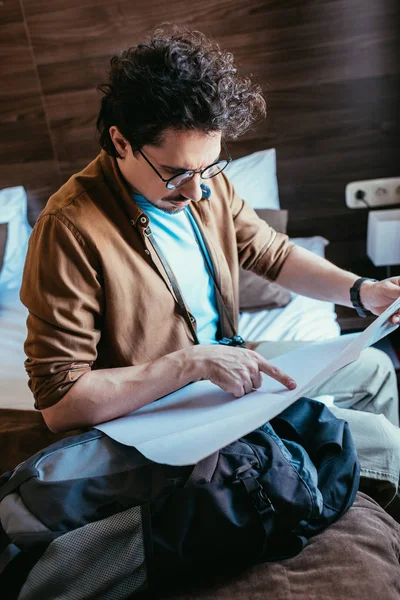 Man in eyeglasses looking at map in hotel room — Stock Photo