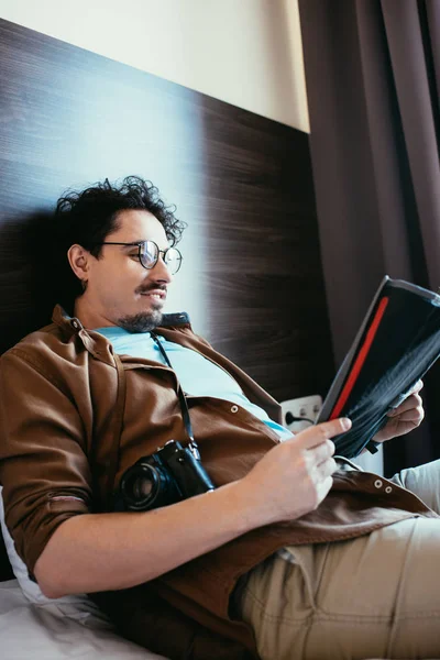 Male traveler with photo camera looking at map in hotel room — Stock Photo