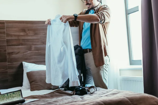 Turista masculino colocando camisa em mochila no quarto de hotel — Fotografia de Stock