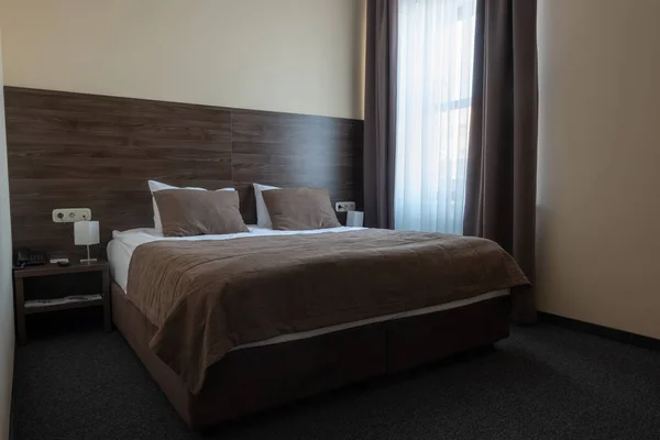 Chambre d'hôtel intérieur avec fenêtre et lit marron — Photo de stock