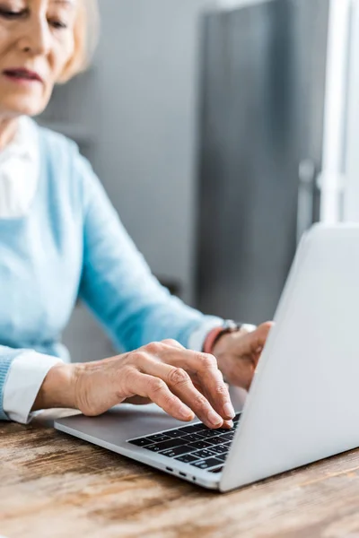 Partial view of senior woman typing on laptop at home — Stock Photo
