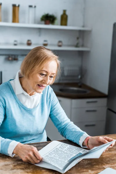 Seniorin sitzt zu Hause und liest Zeitung — Stockfoto