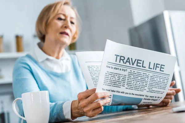 Anziana seduta e lettura giornale di viaggio a casa — Foto stock