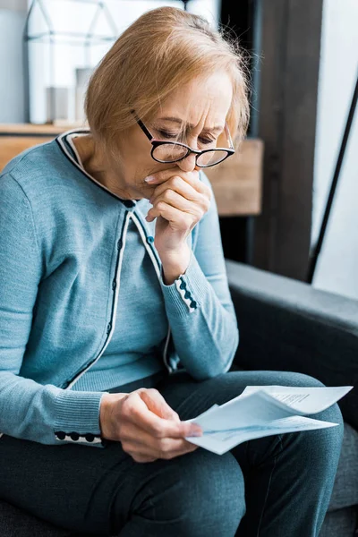 Senior woman covering mouth and looking at tax form at home — Stock Photo