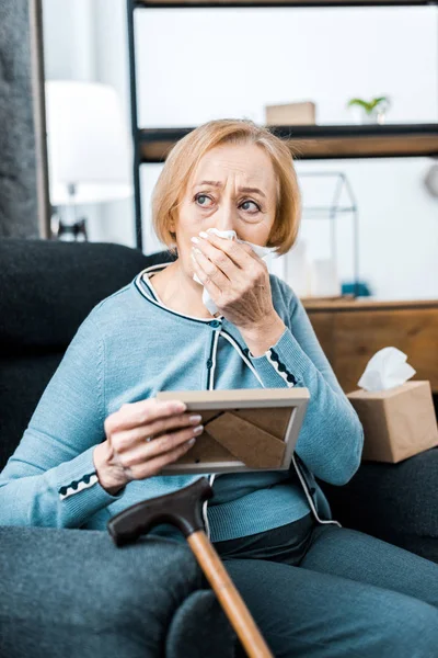 Upset senior woman wiping face from tears, crying and holding picture frame — Stock Photo