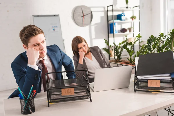 Selective focus of document trays with lettering near tired coworkers, procrastination concept — Stock Photo