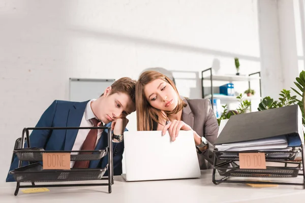 Document trays with lettering near sleepy and and tired woman looking at laptop, procrastination concept — Stock Photo