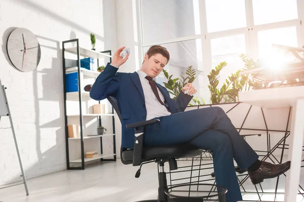 Geschäftsmann sitzt auf Stuhl und wirft Papier in Papierkorb im Büro, Verzögerungskonzept — Stockfoto