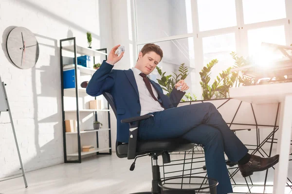 Homme d'affaires assis sur une chaise et jetant du papier dans la poubelle au bureau, concept de temporisation — Photo de stock