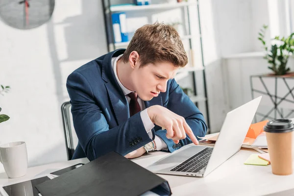 Homme d'affaires insatisfait en utilisant un ordinateur portable tout en étant assis au bureau — Photo de stock