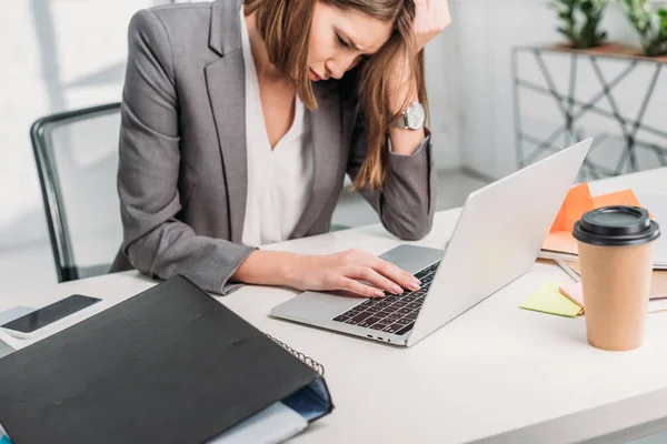 Виснажена приваблива бізнес-леді тримає голову біля ноутбука в офісі — стокове фото