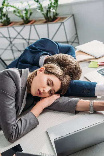 Compañeros de trabajo cansados durmiendo en el escritorio en la oficina - foto de stock