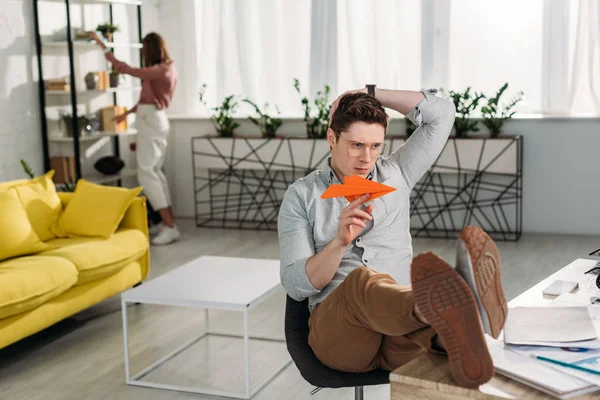 Selective focus of man playing with paper plane with woman on background — Stock Photo
