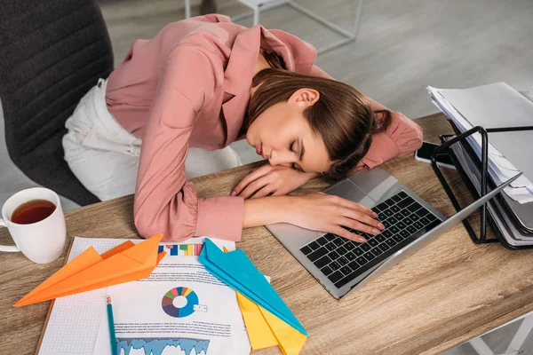 Overhead view of attractive woman sleeping at desk near laptop at home — Stock Photo