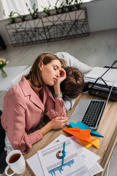 Girlfriend and boyfriend sleeping at desk near laptop and cup with drink — Stock Photo