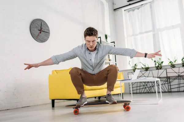 Bell'uomo in occhiali cavalcando skateboard a casa — Foto stock