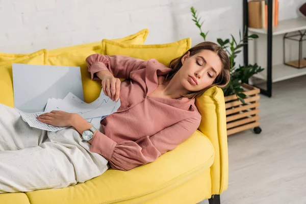 Уставшая женщина спит на диване с документами дома — стоковое фото
