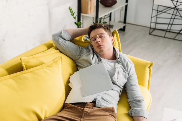 Müder Mann schläft zu Hause auf Sofa mit Dokumenten — Stockfoto