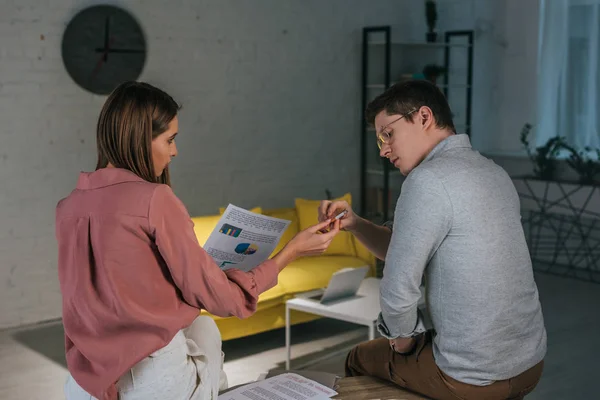 Frau gibt Mann Zigarette in Brille und hält Diagramme und Grafiken in der Hand — Stockfoto