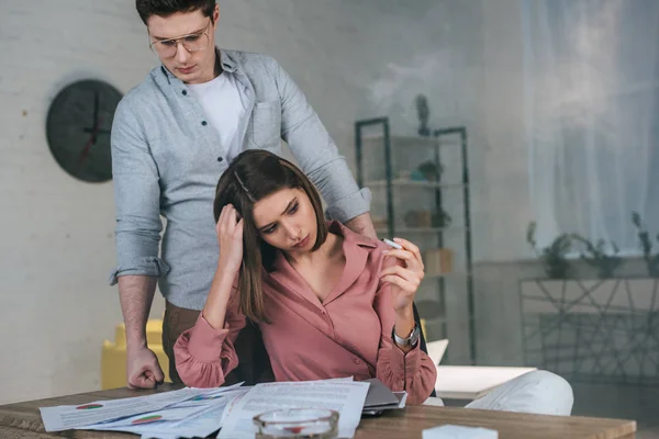 Woman holding cigarette and looking at charts and graphs near man in glasses — Stock Photo