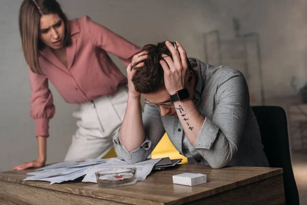 Attractive woman looking at man holding head while having headache — Stock Photo
