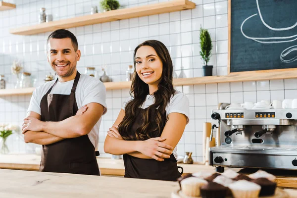 Cajeros de pie detrás del mostrador de la barra y sonriendo en la cafetería - foto de stock