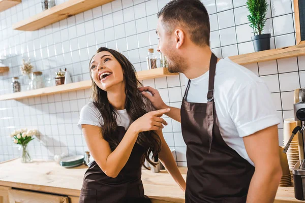 Caixas em aventais falando e rindo perto do balcão de bar na casa de café — Fotografia de Stock