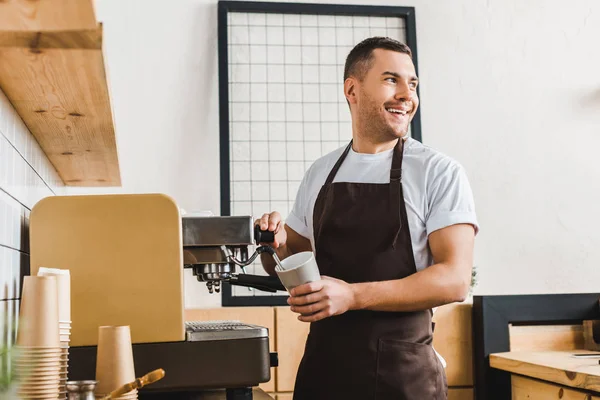 Schöner Barista hält Tasse und kocht Kaffee mit Maschine im Kaffeehaus — Stockfoto