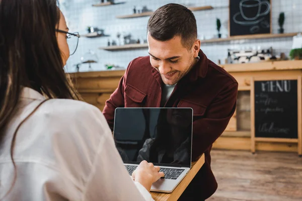 Woman and handsome man in burgundy shirt sitting at table with laptop in coffee house — Stock Photo