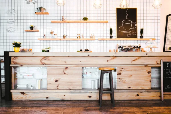Wooden brown bar counter with plants and cupcakes, drawing on shelf in coffee house — Stock Photo