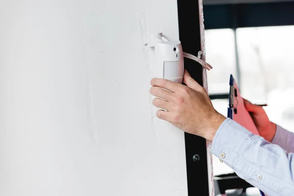 Vue recadrée du pompier vérifiant l'alarme incendie tout en tenant le presse-papiers et le stylo — Photo de stock