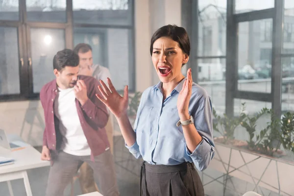 Scared businesswoman standing yelling near coworkers in office with smoke — Stock Photo